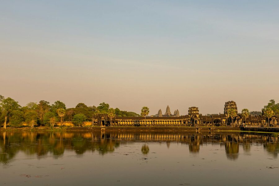 Angkor Wat temple reflecting in calm waters at sunrise