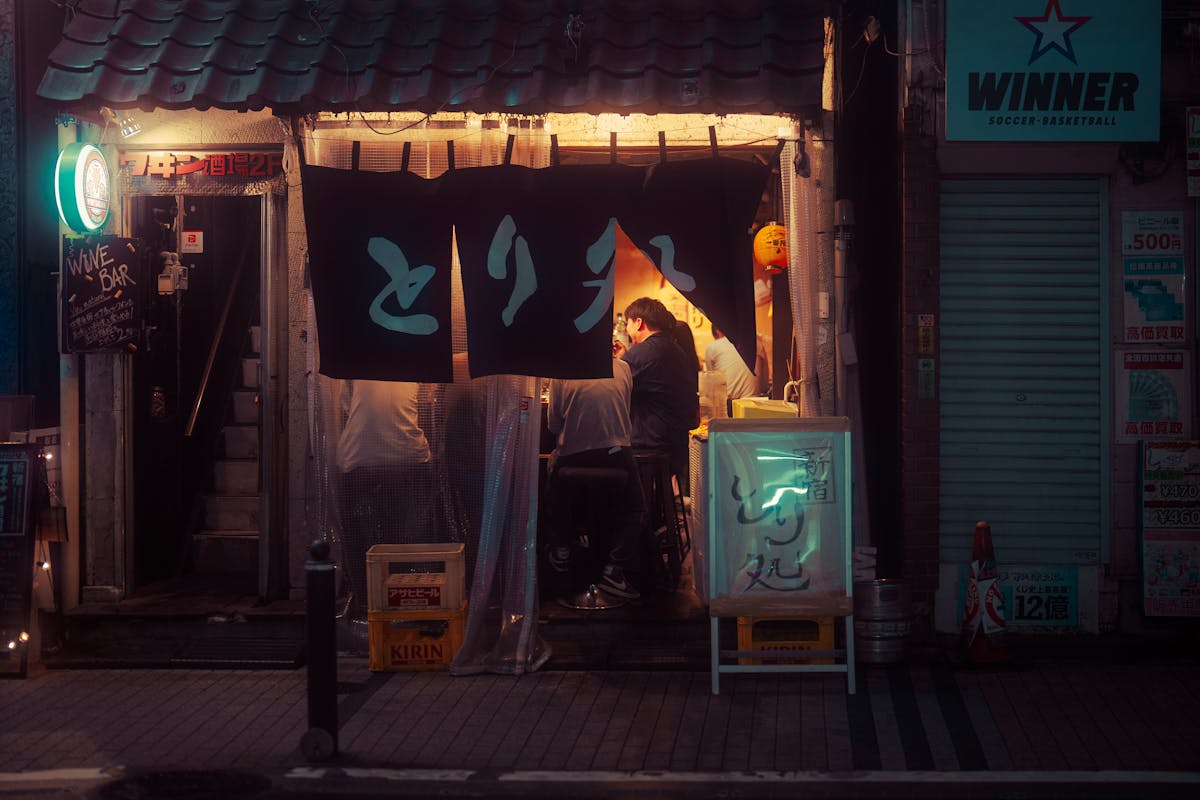 Interior of a cozy izakaya in Tokyo with warm lighting and hanging paper lanterns