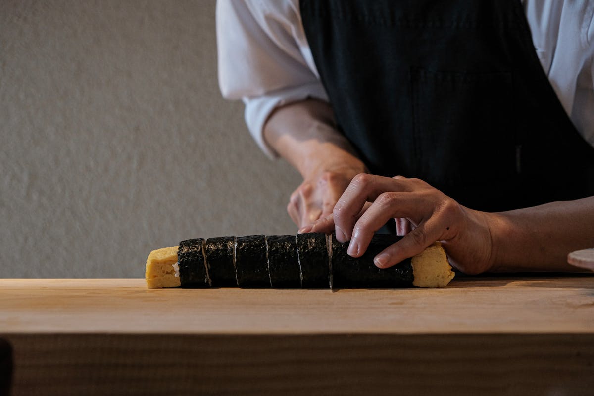 Close-up of a chef hands slicing a sushi roll highlighting the precision of sushi making