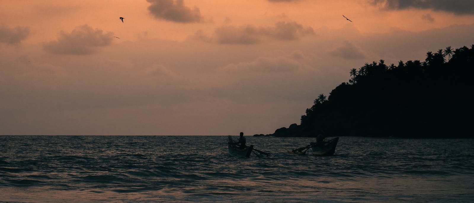 Two fishermen casting nets at sunset in Mirissa Sri Lanka