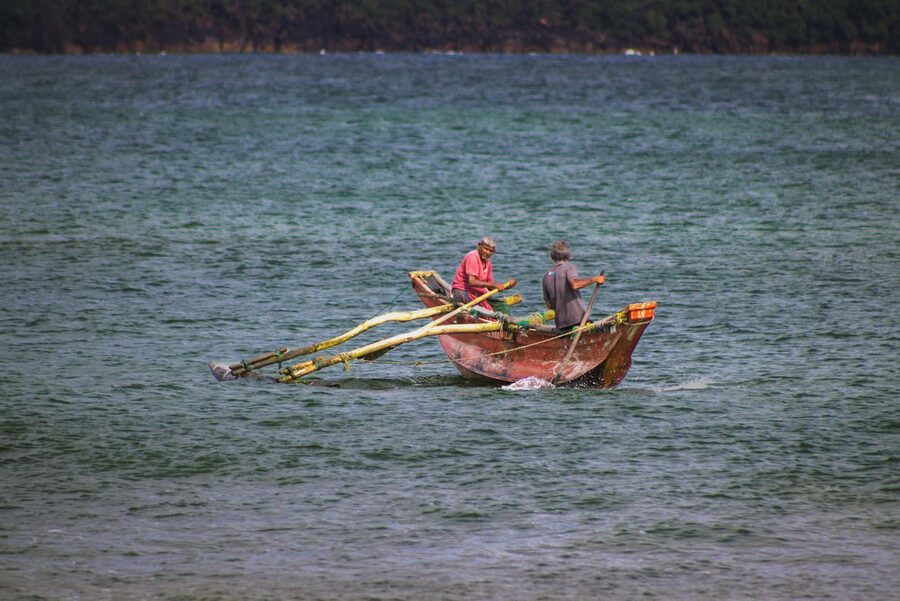 Two fishermen rowing a traditional boat on the ocean in Galle Sri Lanka