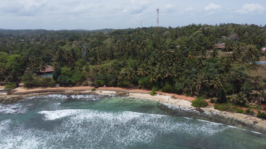 Aerial drone view of the lush green coastline of southern Sri Lanka with turquoise water