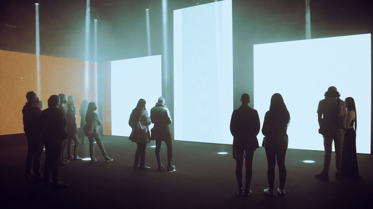 Visitors walking through an immersive digital art exhibition with large illuminated projections