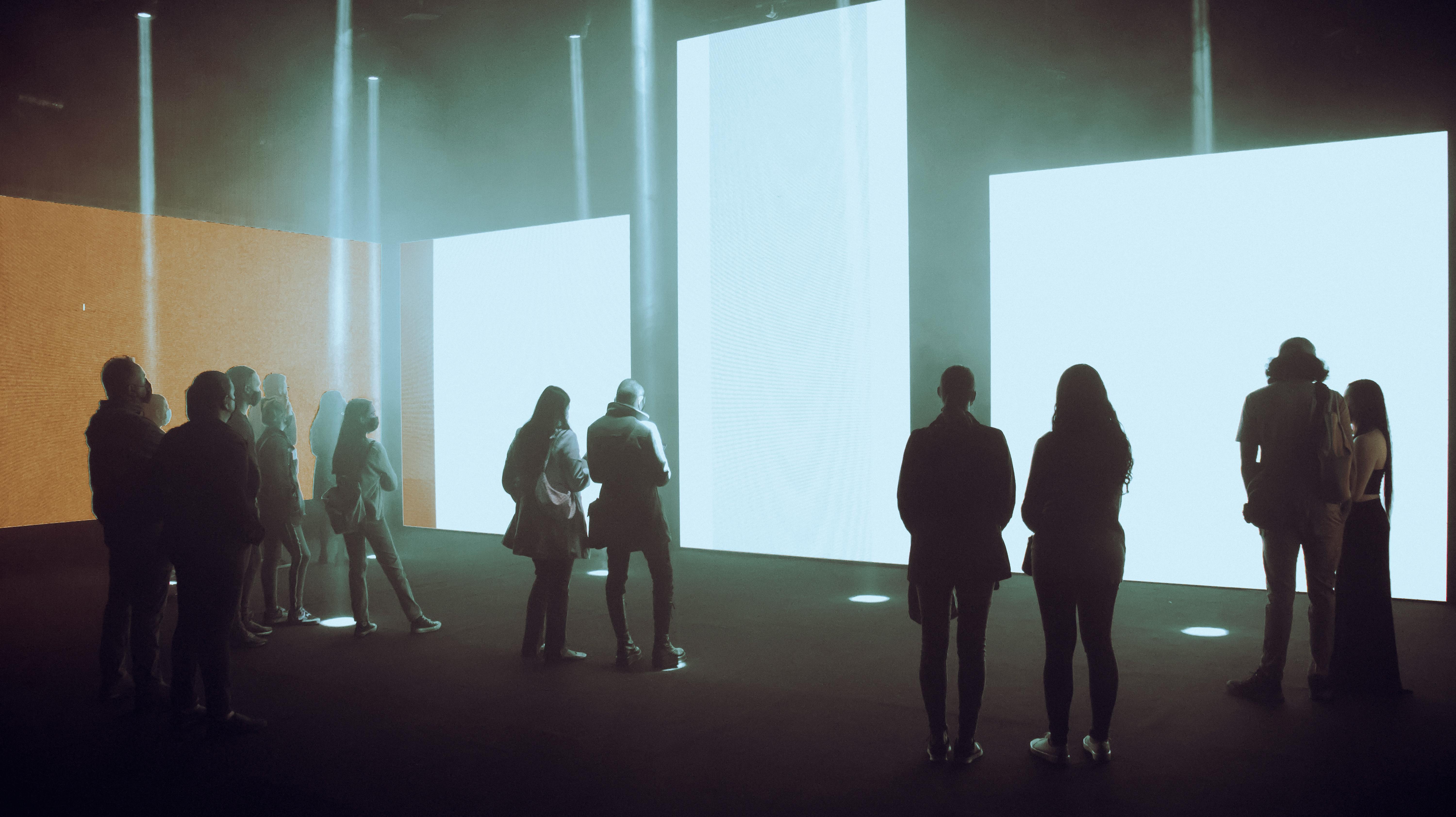 Visitors exploring an immersive digital art exhibition with illuminated screens