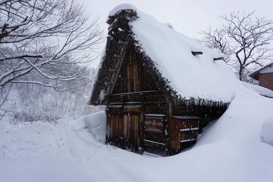 A historic gassho-zukuri farmhouse covered in deep snow in the winter landscape of Shirakawa-go Japan