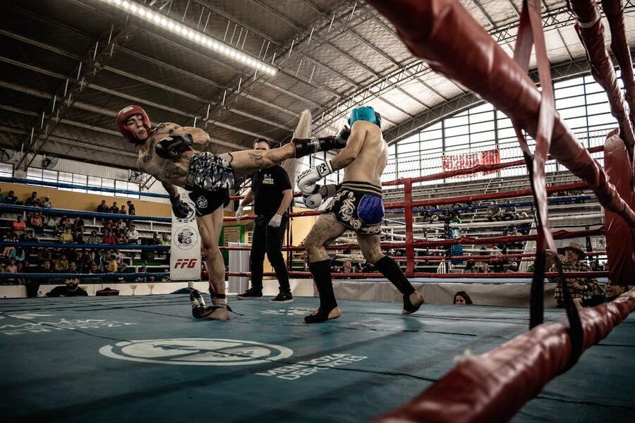 Kickboxing match with athletes exchanging kicks in a packed arena