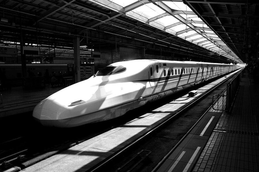 A white shinkansen bullet train arriving at a Japanese train station platform