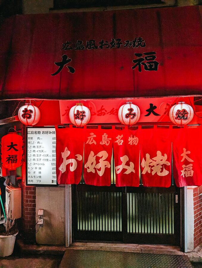 Entrance to a traditional Japanese restaurant with red lanterns and warm lighting