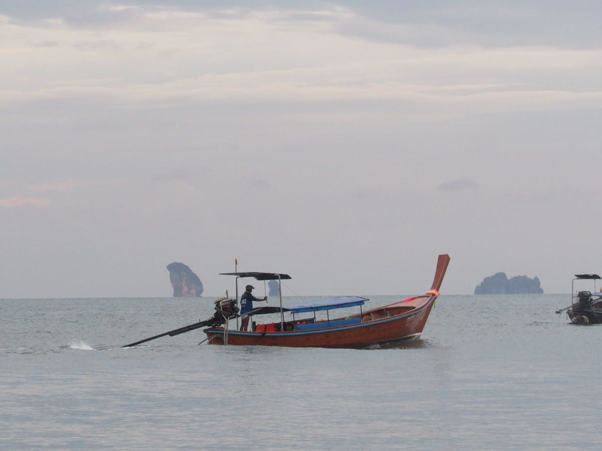 Traditional Thai longtail boat on calm ocean with islands in the distance