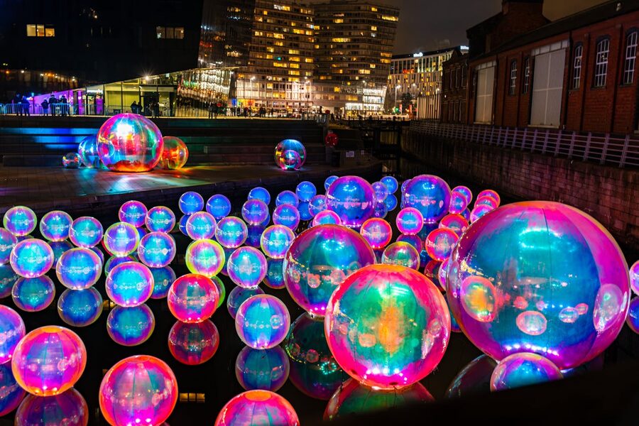 Colorful illuminated spheres reflecting on water surface in a night city setting