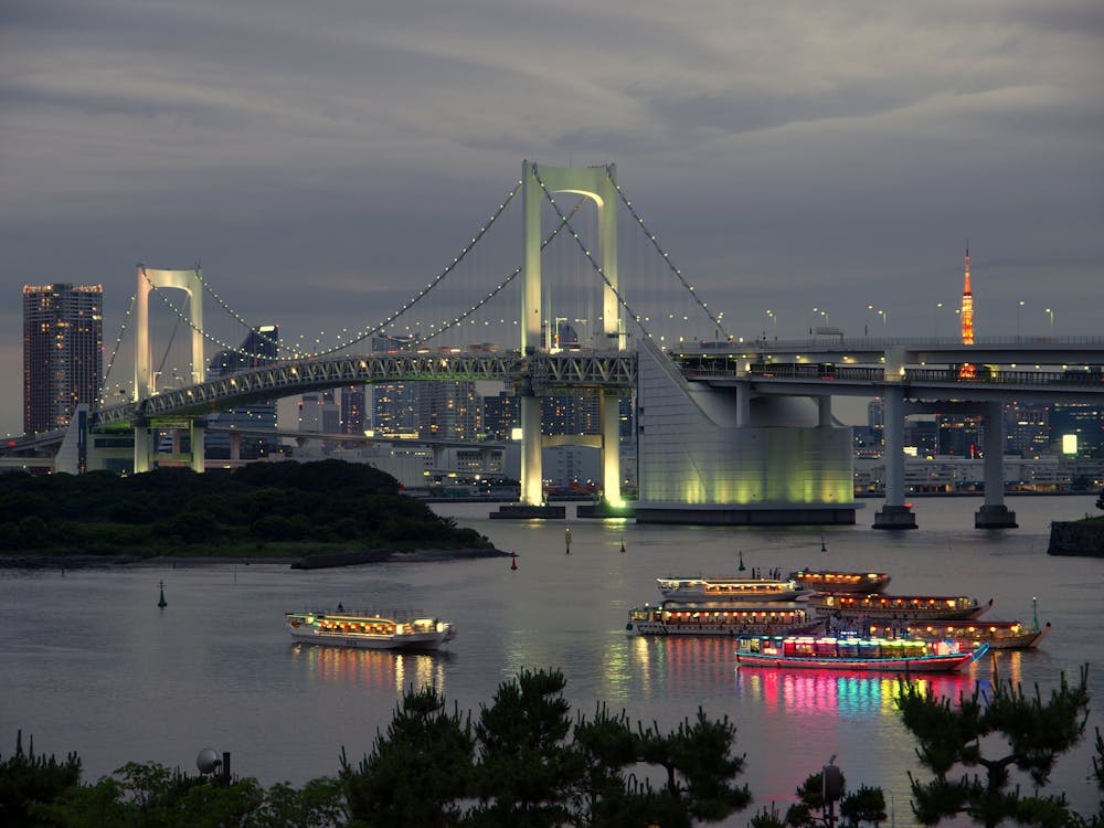 Rainbow Bridge in Tokyo illuminated at night with colorful lights reflecting on the water