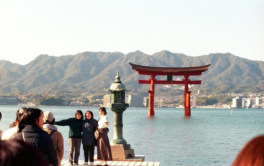 Tourists walking near the famous floating torii gate at Miyajima island