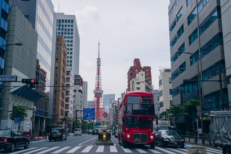 Red sightseeing bus on a Tokyo street with Tokyo Tower visible in the background