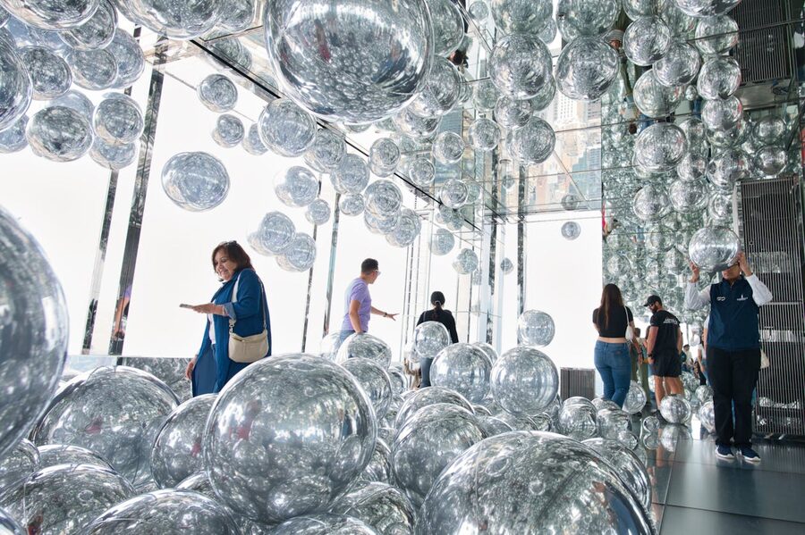 Visitors exploring a reflective art installation with mirrored spheres
