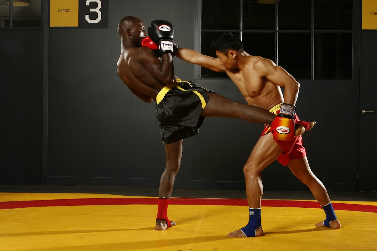 Two athletes sparring in a boxing ring under indoor lighting