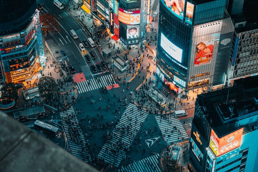 Aerial shot of the Shibuya Crossing in Tokyo at night with bright lights