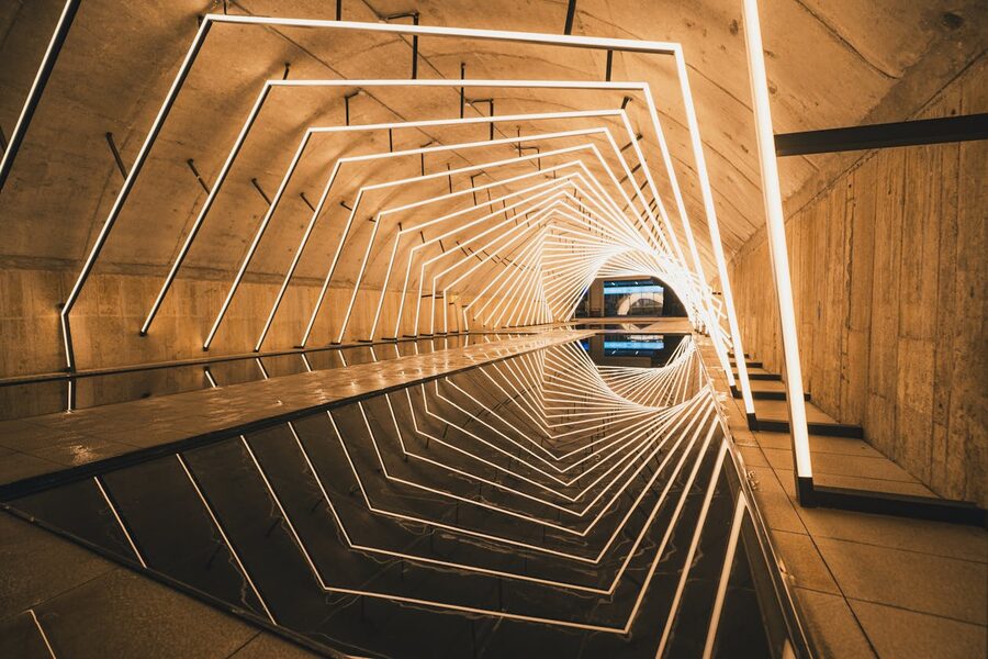 Tunnel with geometric LED light patterns reflecting on a wet floor surface