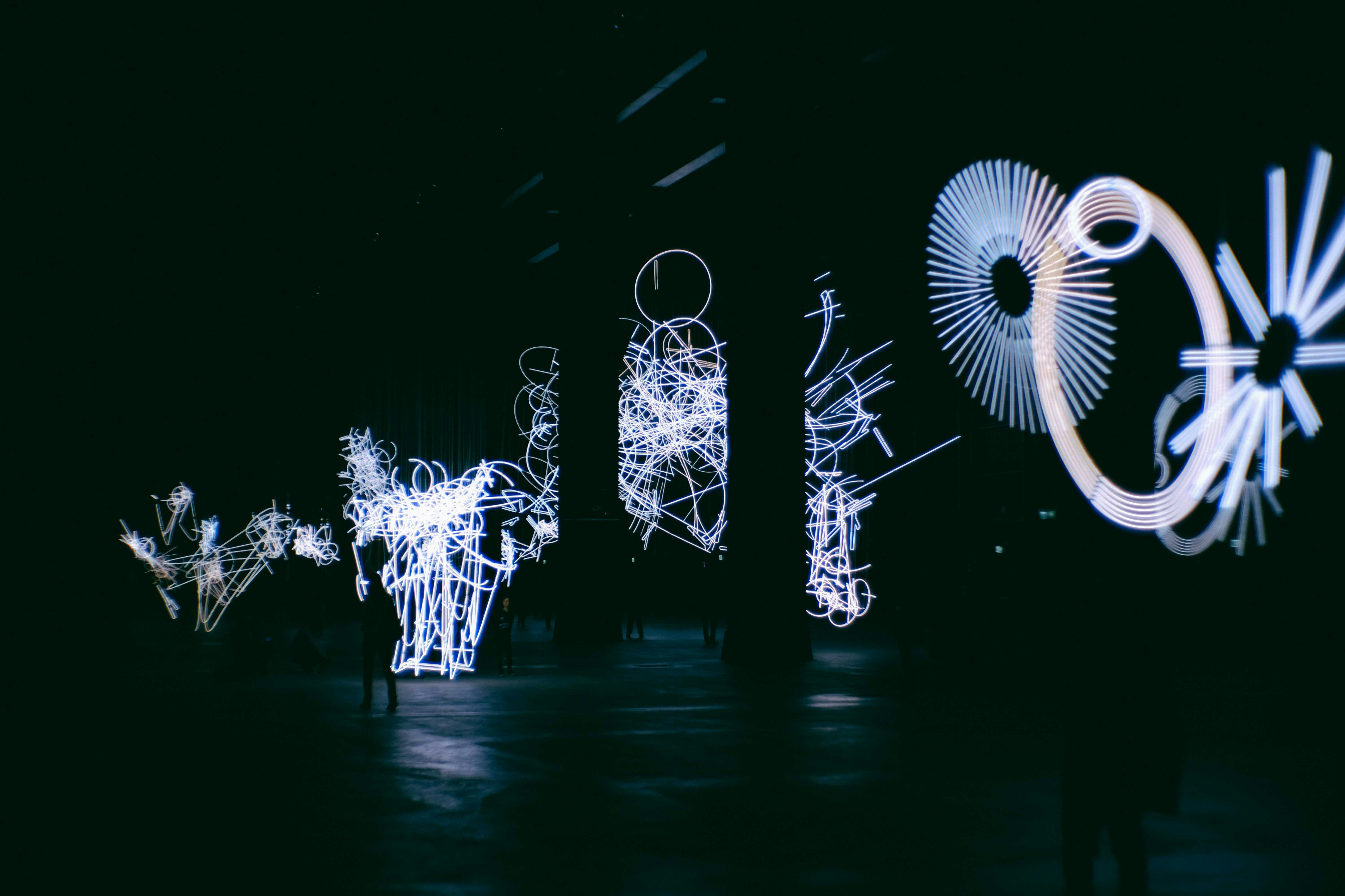 Artificial light figures with circles and wavy lines glowing in darkness