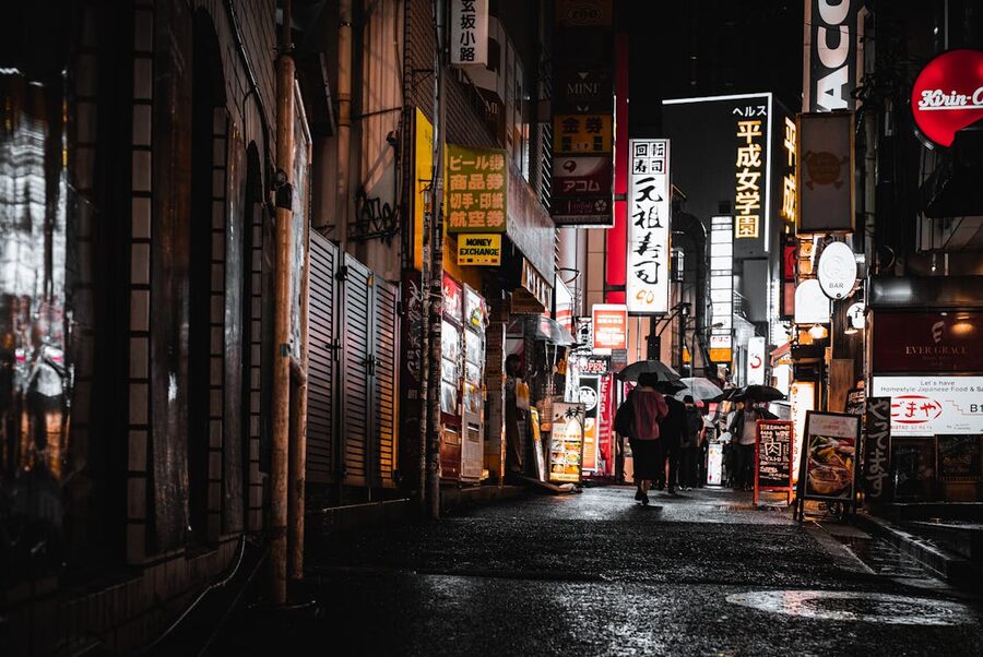 People walking under umbrellas on a rainy night in Tokyo with neon lights