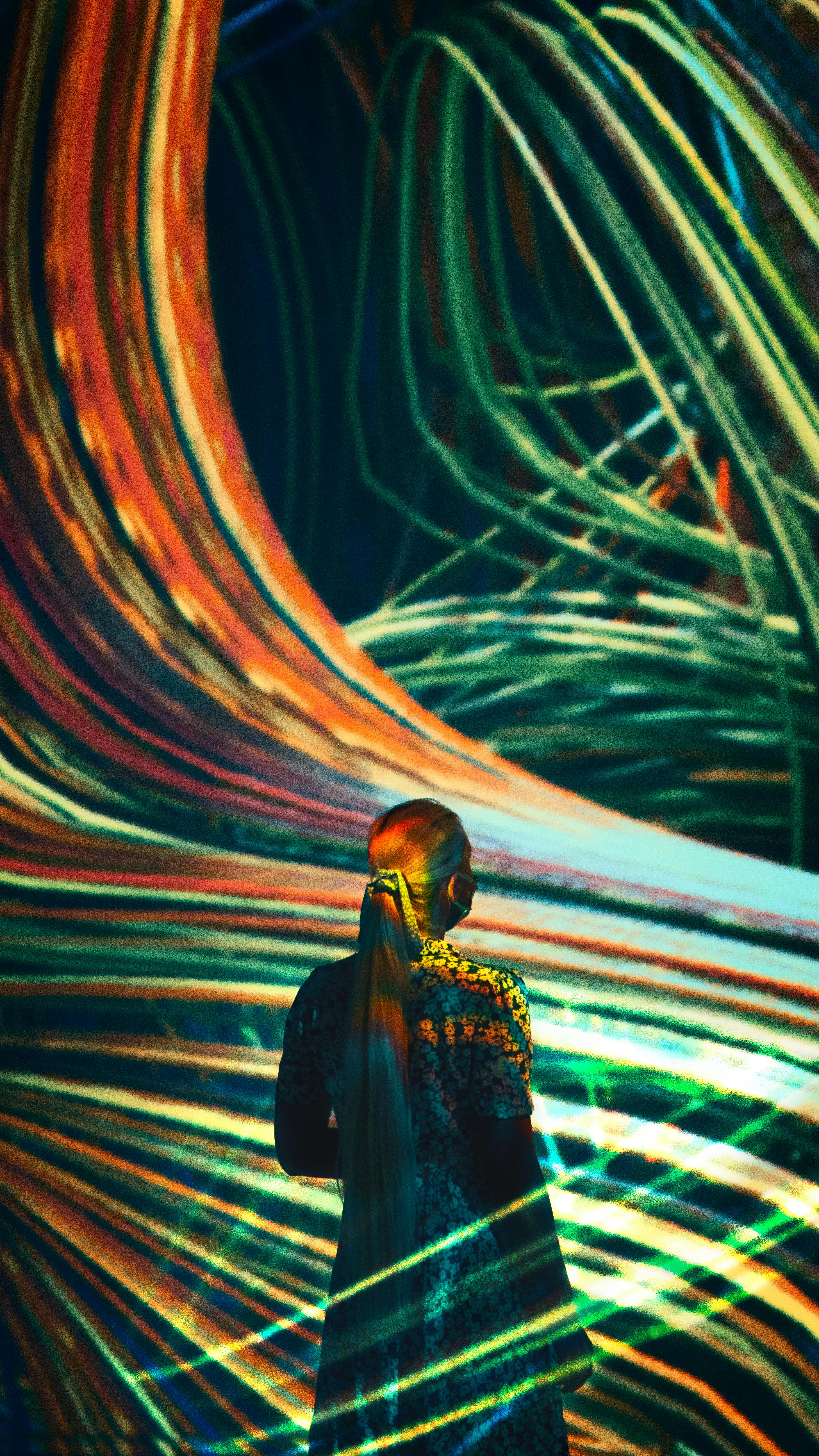 Woman immersed in colorful digital light art creating abstract patterns
