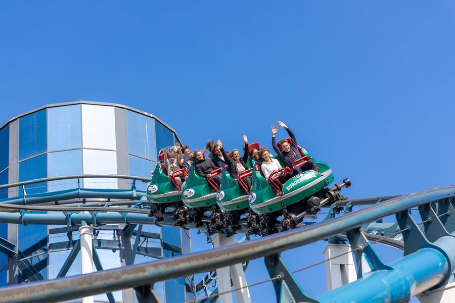 Roller coaster mid-loop with riders against blue sky