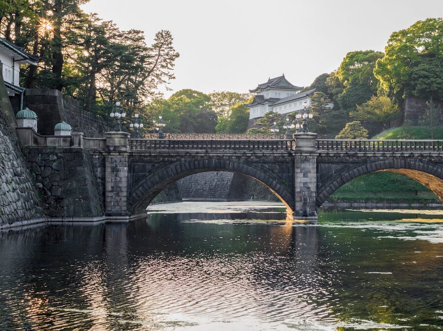 The Seimon Ishibashi bridge at the Imperial Palace in Tokyo surrounded by green trees and reflected in the moat