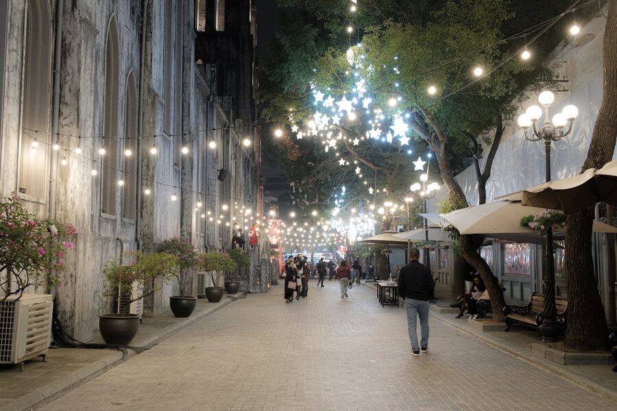 Charming night street in Hanoi with festive string lights and people walking