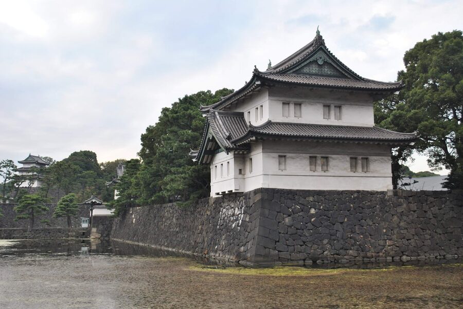 Exterior view of the Tokyo Imperial Palace grounds with massive stone fortification walls and surrounding green vegetation