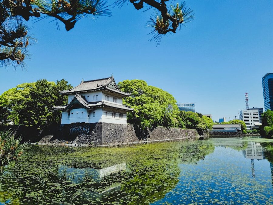 A traditional Japanese guardhouse building reflected in a still pond in the Imperial Palace East Gardens