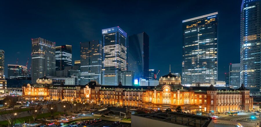 Night view of Tokyo Station illuminated with tall skyscrapers behind it in Chiyoda City