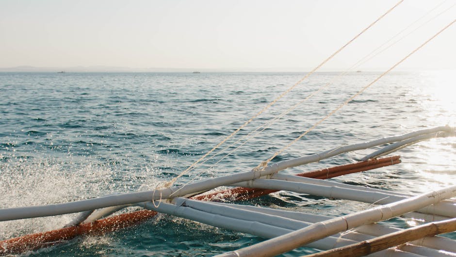 Traditional Philippine banca outrigger boat sailing across calm ocean water