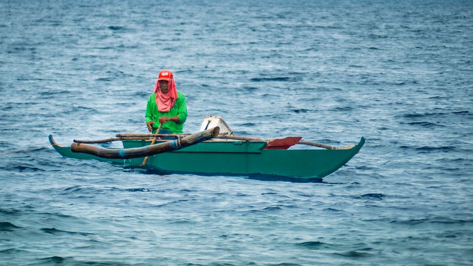Clear turquoise sea with a traditional Filipino fishing boat and islands in the distance