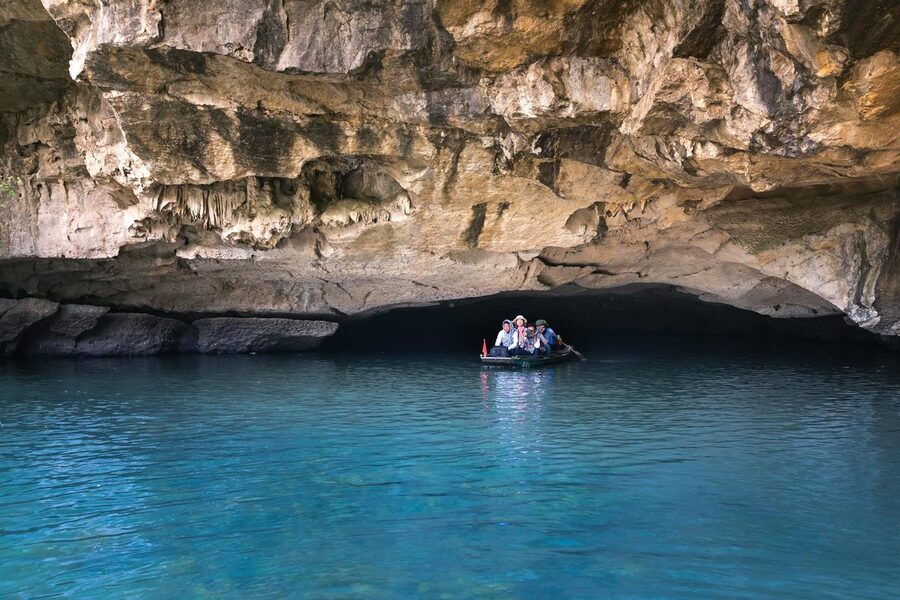 Tourists on a boat passing through a limestone sea cave with clear blue water