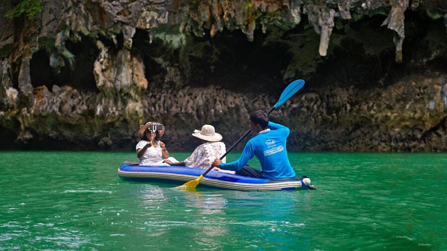 Group of kayakers paddling through a limestone cave passage in Krabi Thailand