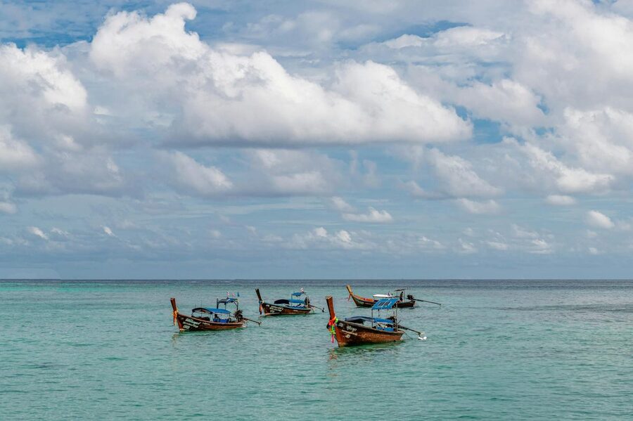 Traditional Thai longtail boats floating on crystal clear turquoise water in Phuket