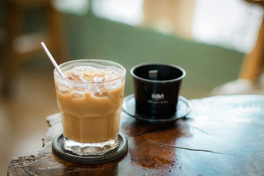 Extreme close-up of a Vietnamese phin brewing coffee into a glass with condensed milk
