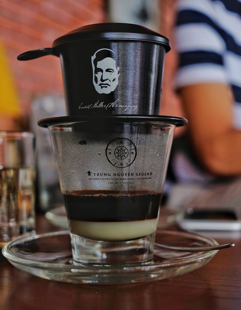Close-up of a Vietnamese phin filter dripping fresh coffee into a small cup