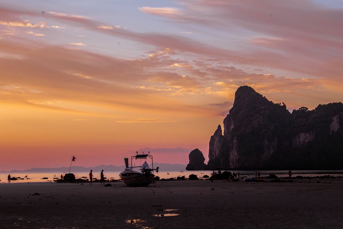 Golden sunset over Phi Phi Islands beach with boats and cliffs