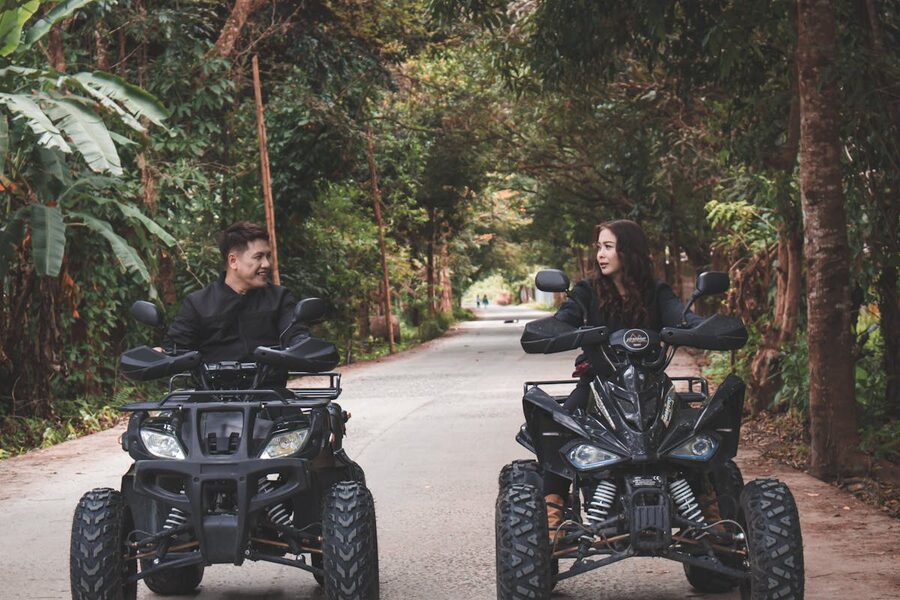 Couple riding quad bikes through a lush green tropical trail