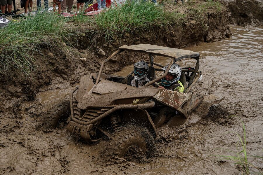ATV riding through muddy terrain with splashing mud