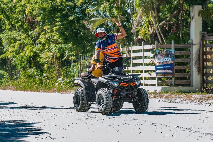 Person riding an ATV on a road surrounded by tropical greenery