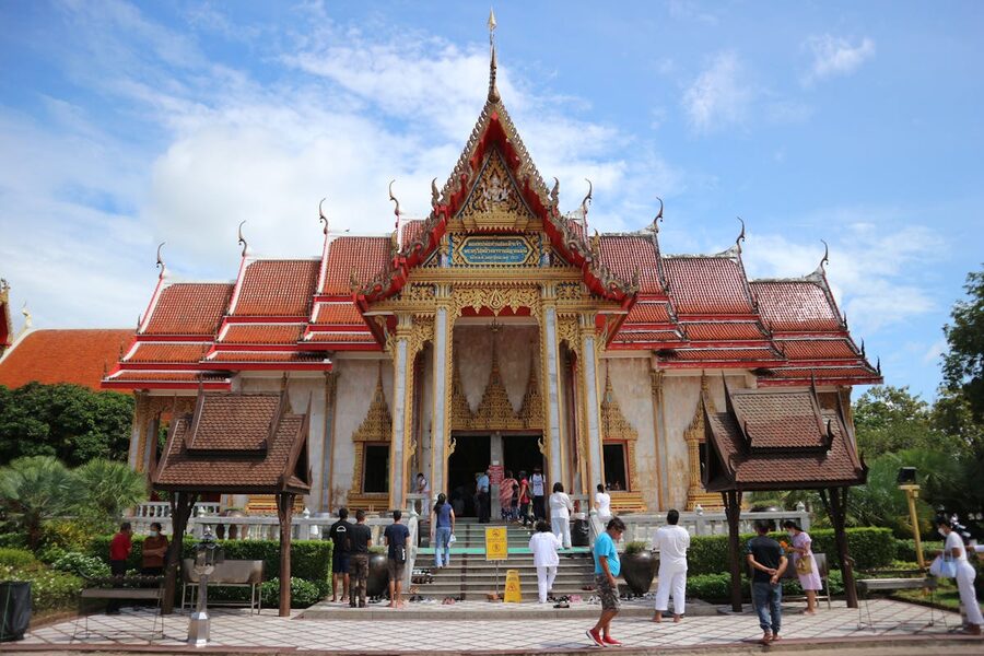 Visitors at Wat Chalong temple in Phuket under blue skies