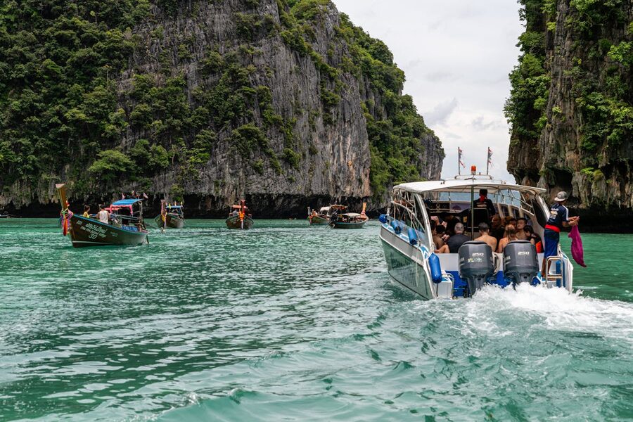 Tourists on speedboat between dramatic limestone cliffs in Phuket Thailand