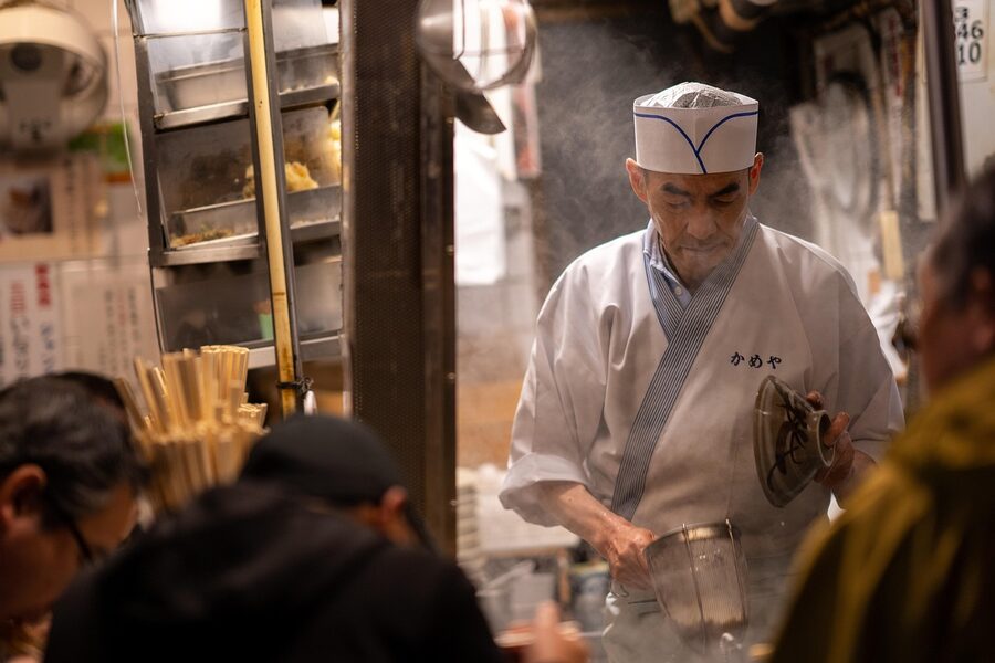Chef grilling yakitori at an outdoor street stall in Shinjuku Tokyo at night