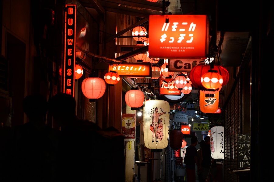 Narrow Japanese alley at night with lit izakaya signs and lanterns
