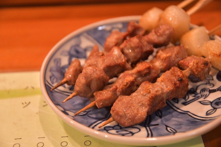 Skewers of yakitori grilling over charcoal at a Japanese food stall