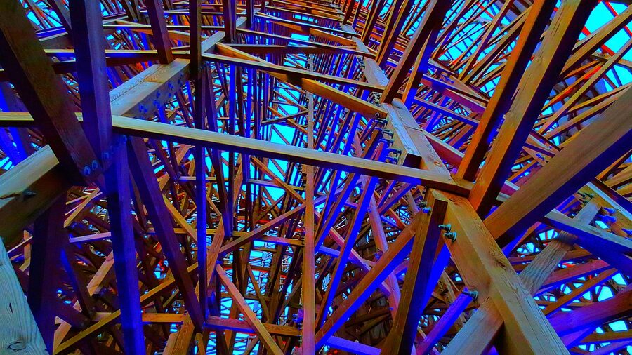 Wooden roller coaster lit blue and violet at dusk