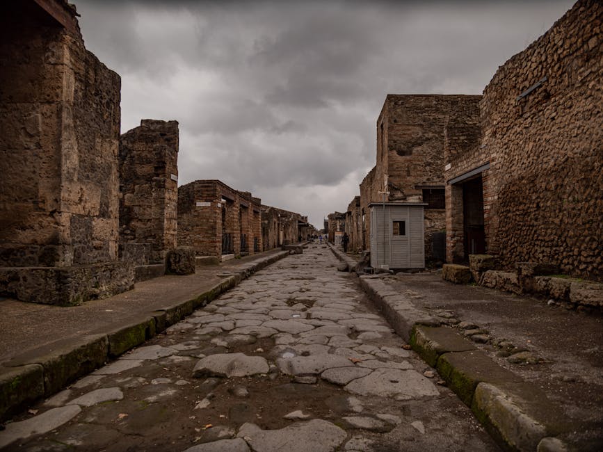 Ancient deserted street in Pompeii Italy with stone walls and an overcast sky