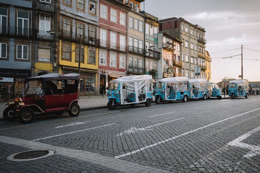 Row of tuk-tuks lined along Porto buildings at dusk