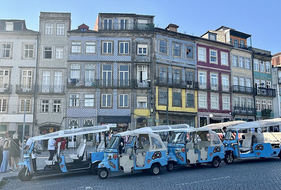 Porto tuk-tuk waiting area with branded vehicles parked along the kerb